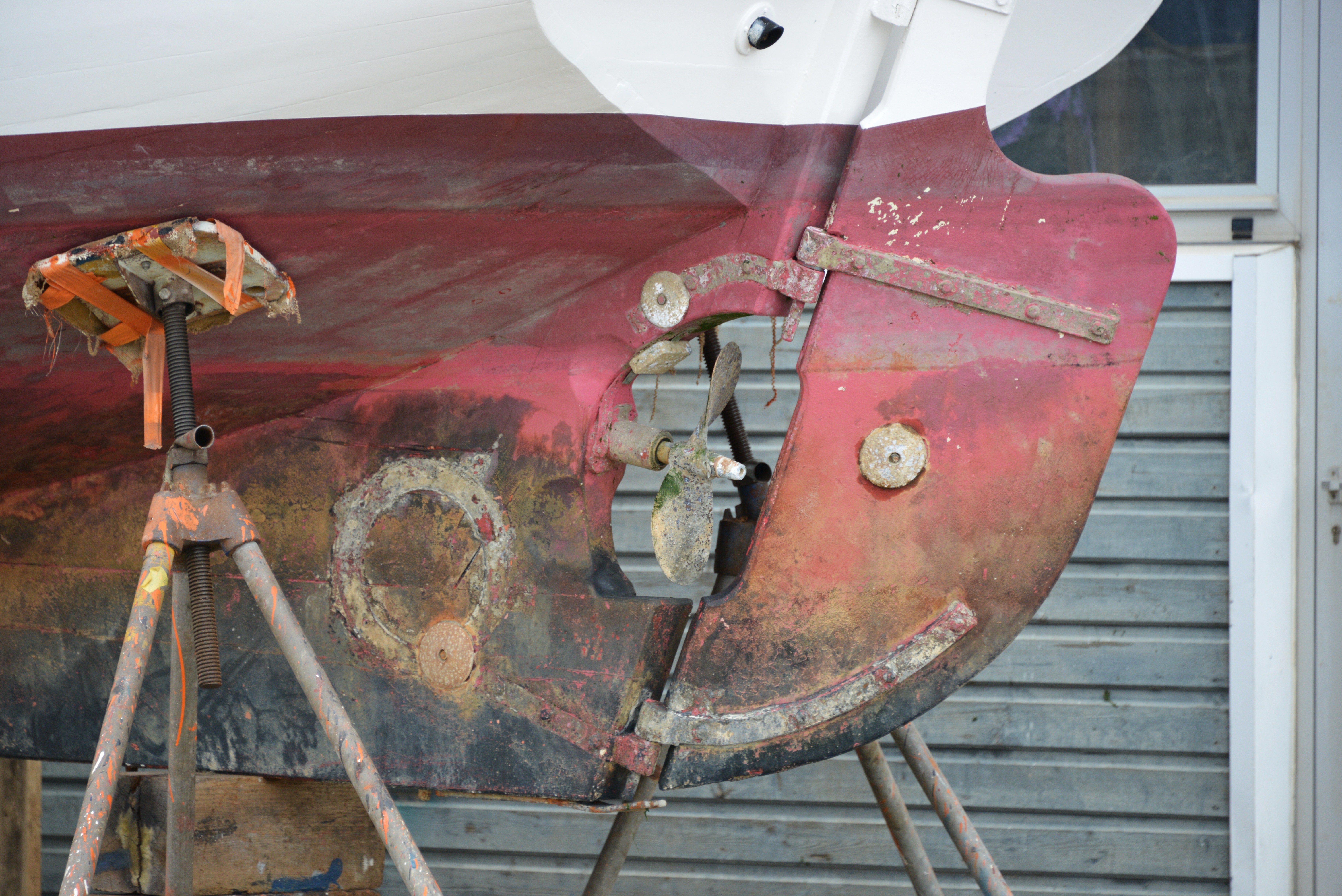 Historic sailboat resting on maintenance supports during yard work
